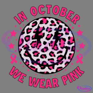 A graphic with the text "In October We Wear Pink" surrounding a leopard print smiley face design. The print is white with pink and black patches, accented by lightning bolt eyes. Pink ribbons and stars outline the circular design, promoting breast cancer awareness.