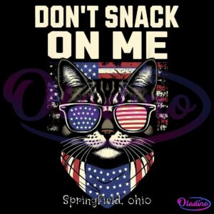 Illustration of a cat wearing sunglasses and a bandana with the American flag pattern. The bold text above reads "DON'T SNACK ON ME" in large, distressed letters. Below the cat is the text "Springfield, Ohio" in smaller, white letters.